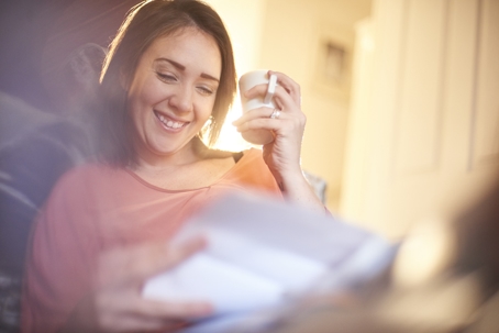 A woman relaxing with a cup of coffee while reading, reflecting a sense of calm and mental relief after resolving financial stress.