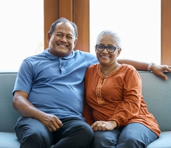 Older couple smiles while on a couch