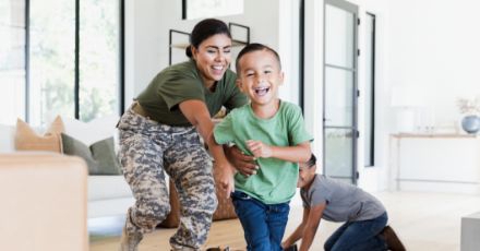 Woman in military garb plays with her children