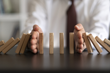 Protecting assets from creditors concept with hands stopping falling blocks.
