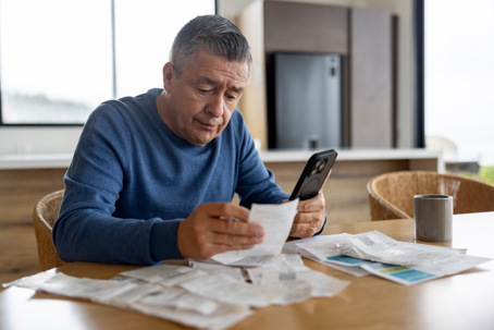 Man reviewing bills and expenses while experiencing financial stress.